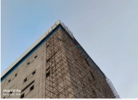 Scaffolded corner elevation showing the building's full 31 M reach.
